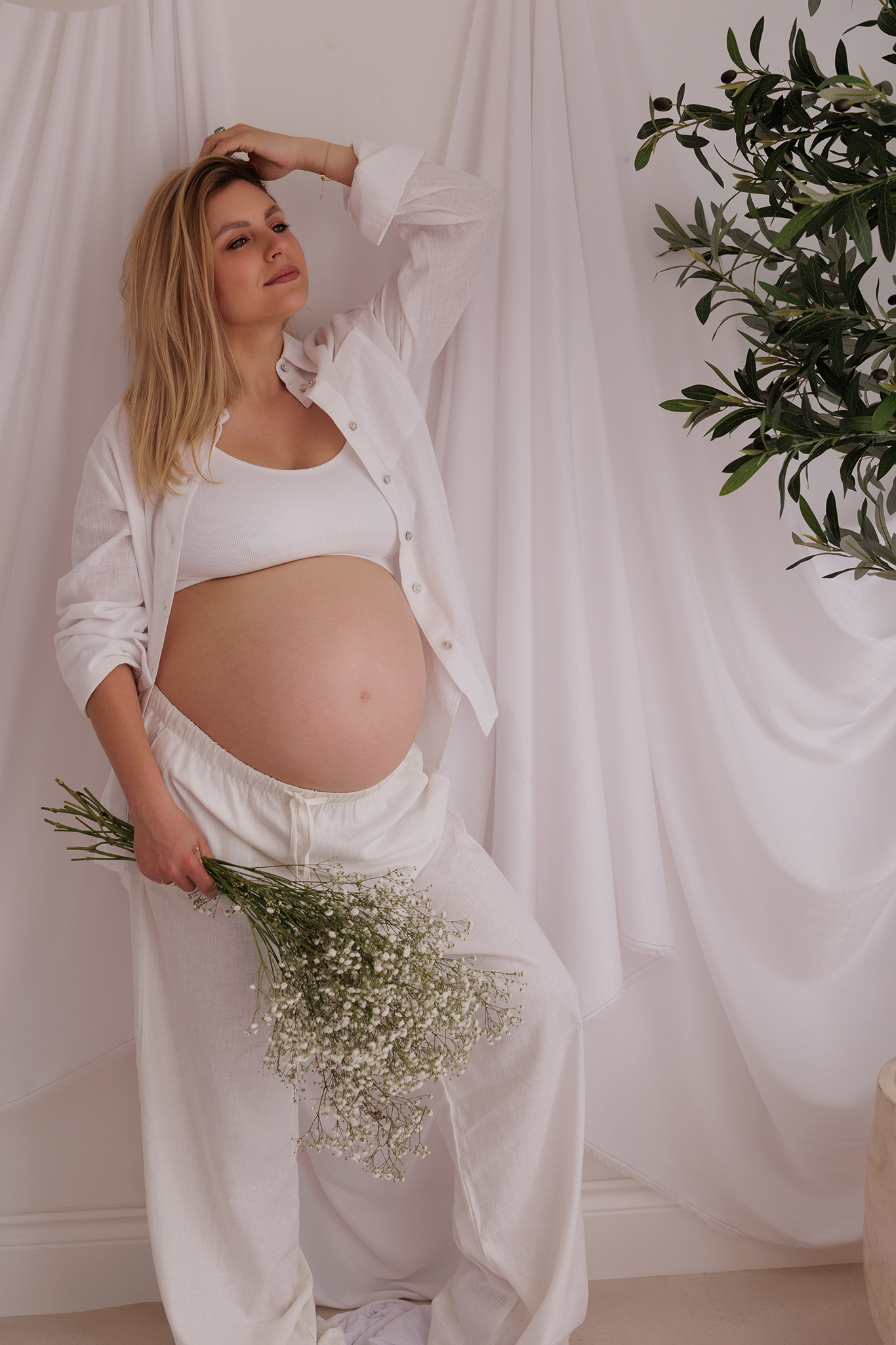 natural maternity photo of pregnant women in soft light wearing neutral shit and trousers